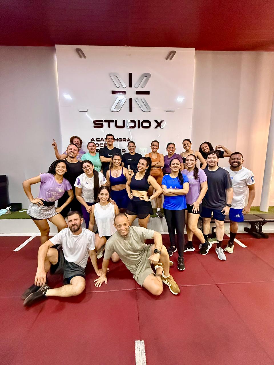 Turma do Studio X posando em frente ao logo da marca
